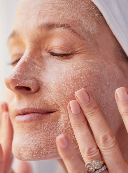 Woman applying a fAnti Ageing 3 Fruit Enzymes Exfoliating Scrub & Mask to her face with a close-up view.