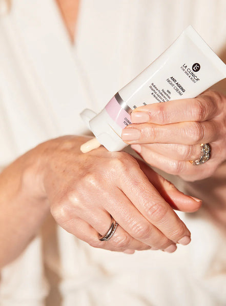 Person applying a Anti Ageing Night Cream With Tripeptides to their hand with a focus on the product and action.