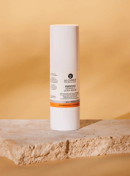 La Clinica Essentials Vitamin C Ultra Serum on a wooden surface with a beige background