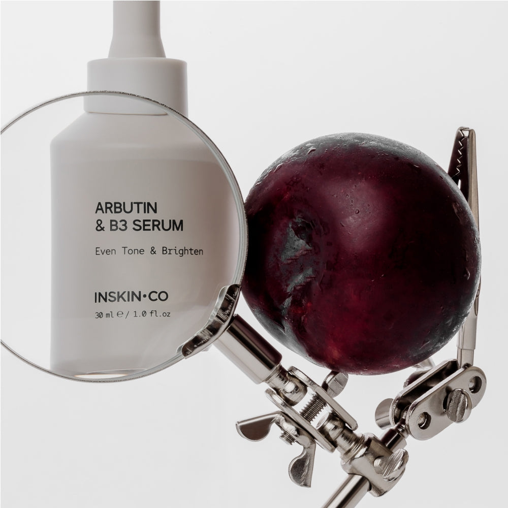INSKIN.CO Arbutin & B3 Serum bottle with a magnifying glass and bearberry plant on a white background