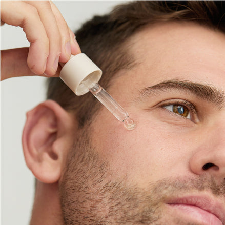 Man applying a dropper of Arbutin & B3 Serum to their face