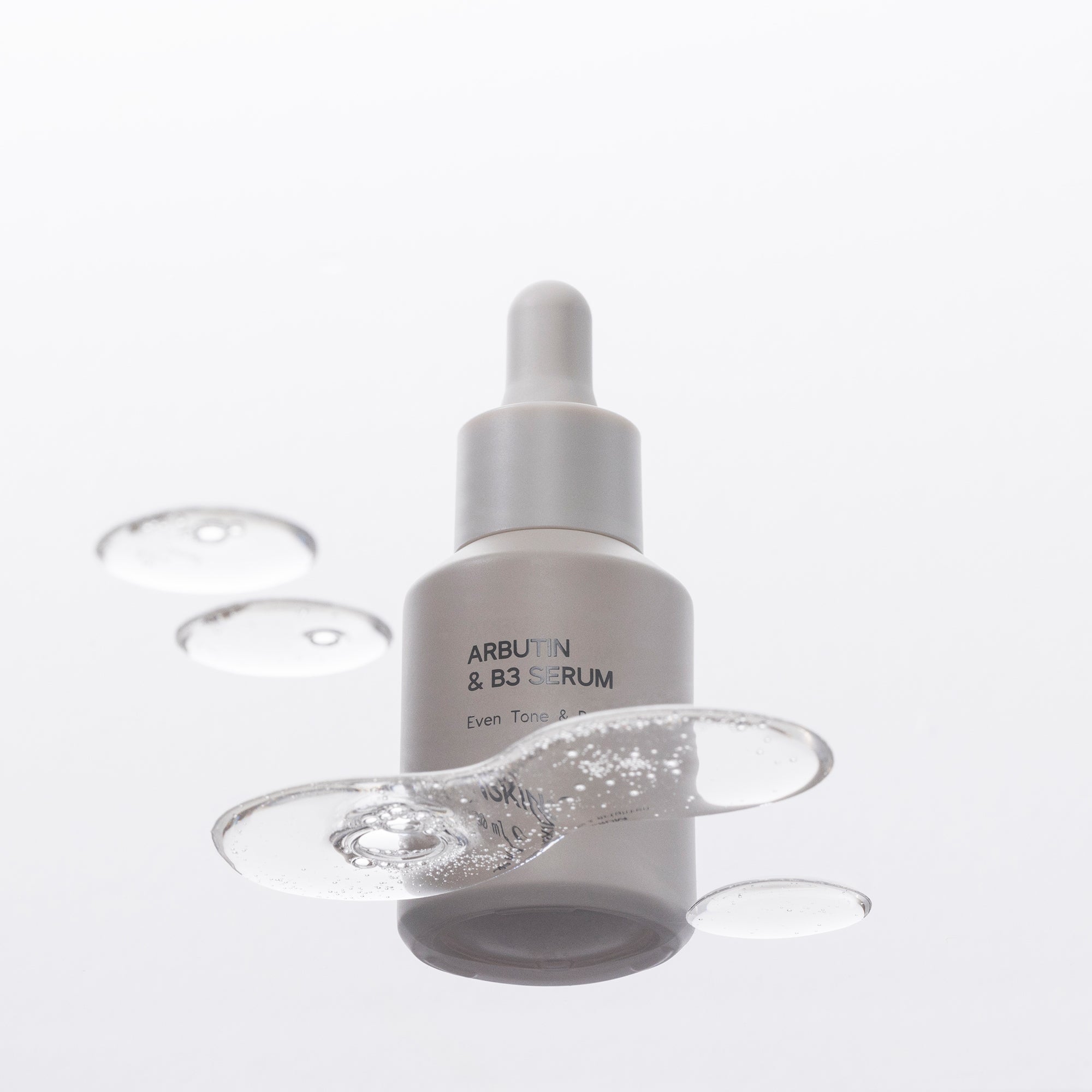 Arbutin & B3 Serum bottle with dropper on a glass background