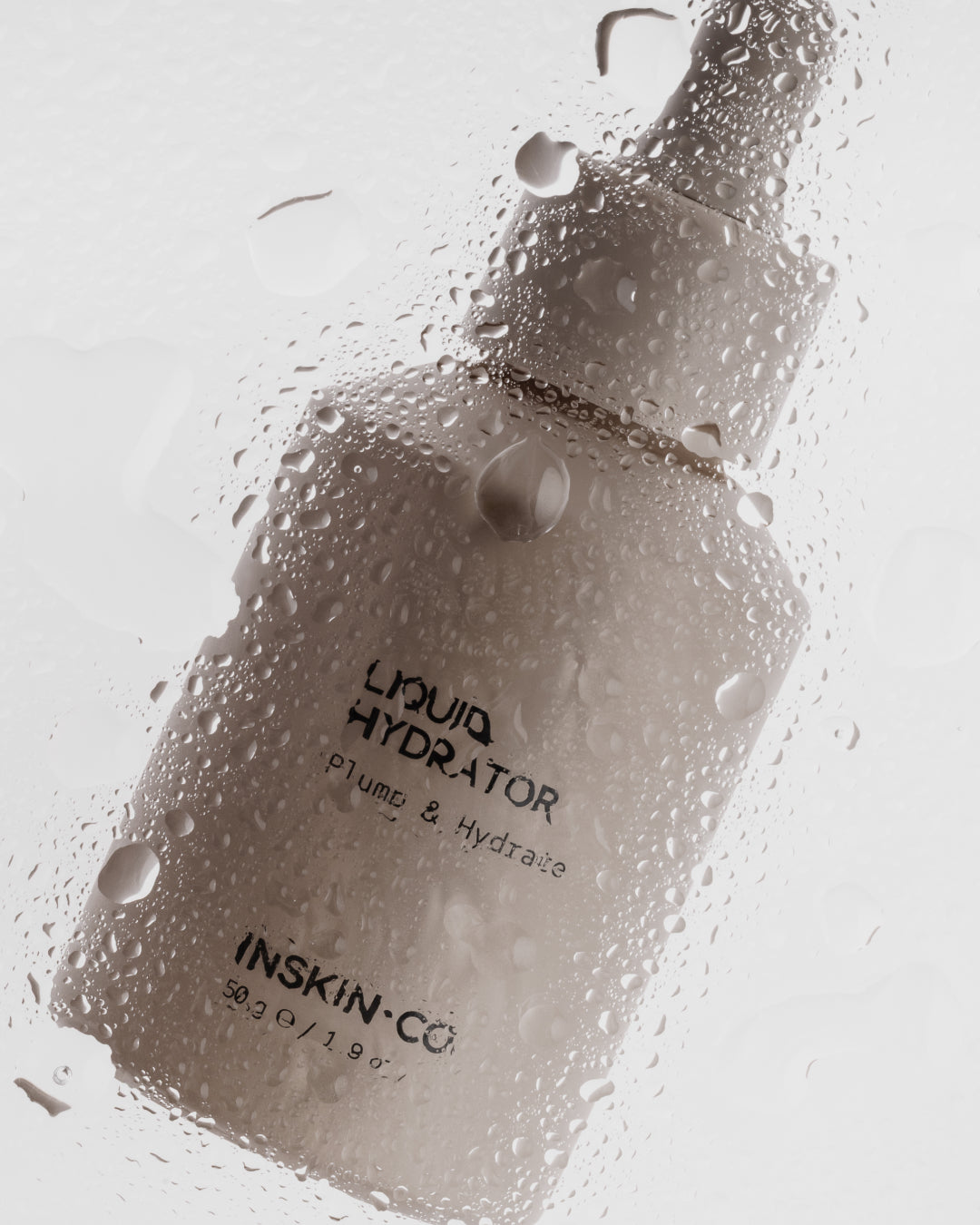 Bottle of 'Liquid Hydrator' by INSKIN-CO with water droplets on a glass surface