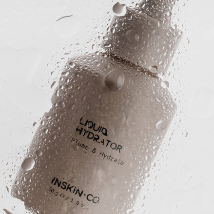 Bottle of 'Liquid Hydrator' by INSKIN-CO with water droplets on a glass surface