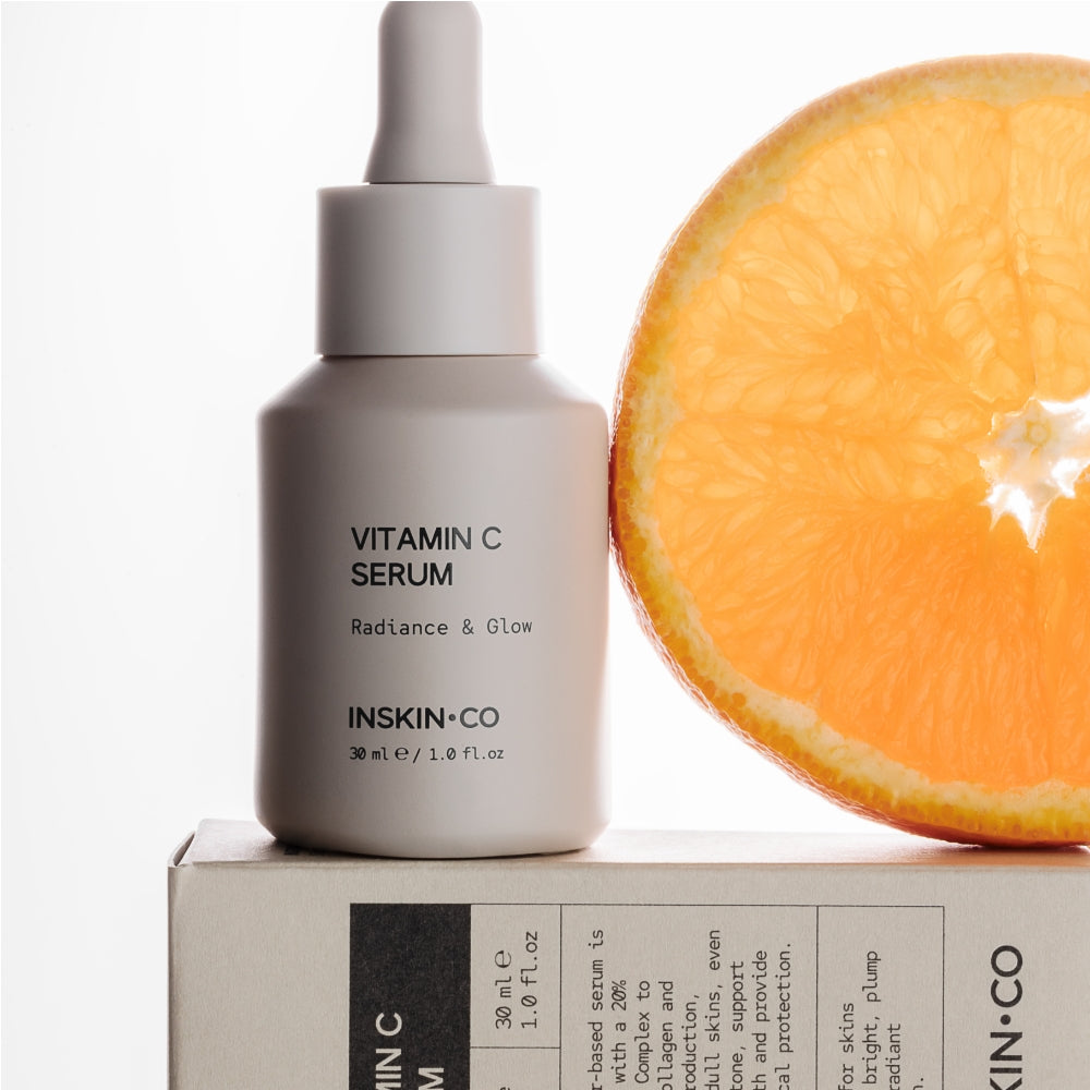 Vitamin C serum bottle and packaging with an orange on a white background