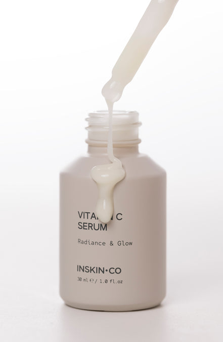 Vitamin C serum being dripped into a bottle labeled 'Inskin Co' on a white background