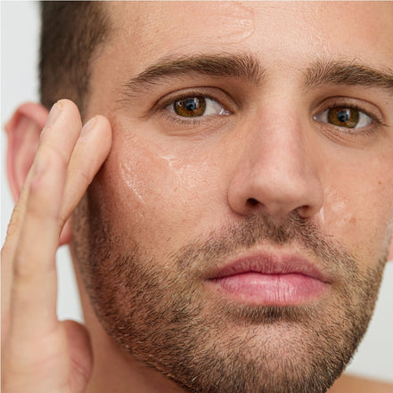 Close-up of a man's face with a focus on applying Vitamin D B5 Serum