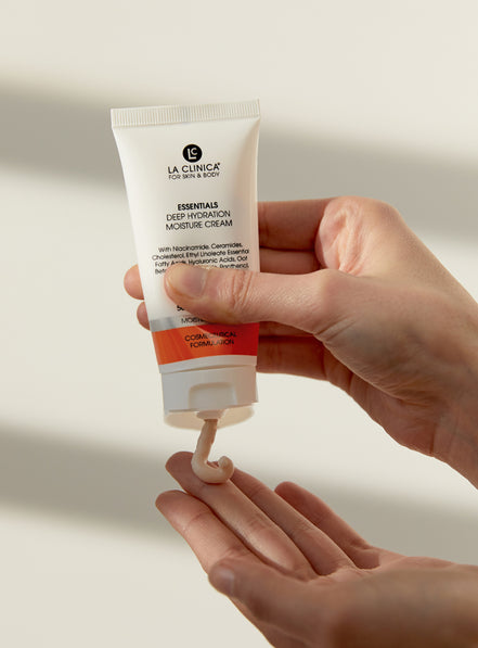 Hand holding a tube of La Clinica Essentials Deep Hydration Moisture Cream with visible cream on the palm.