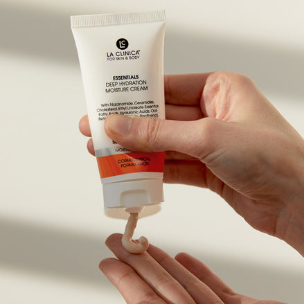 Hand holding a tube of La Clinica Essentials Deep Hydration Moisture Cream with visible cream on the palm.