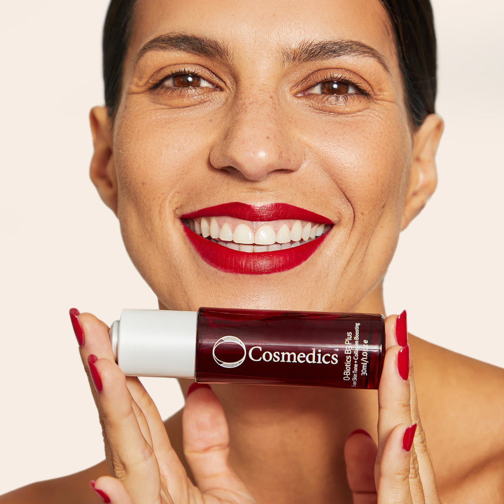 Woman holding 'O' Biotics B3 Plus Serum against a beige background
