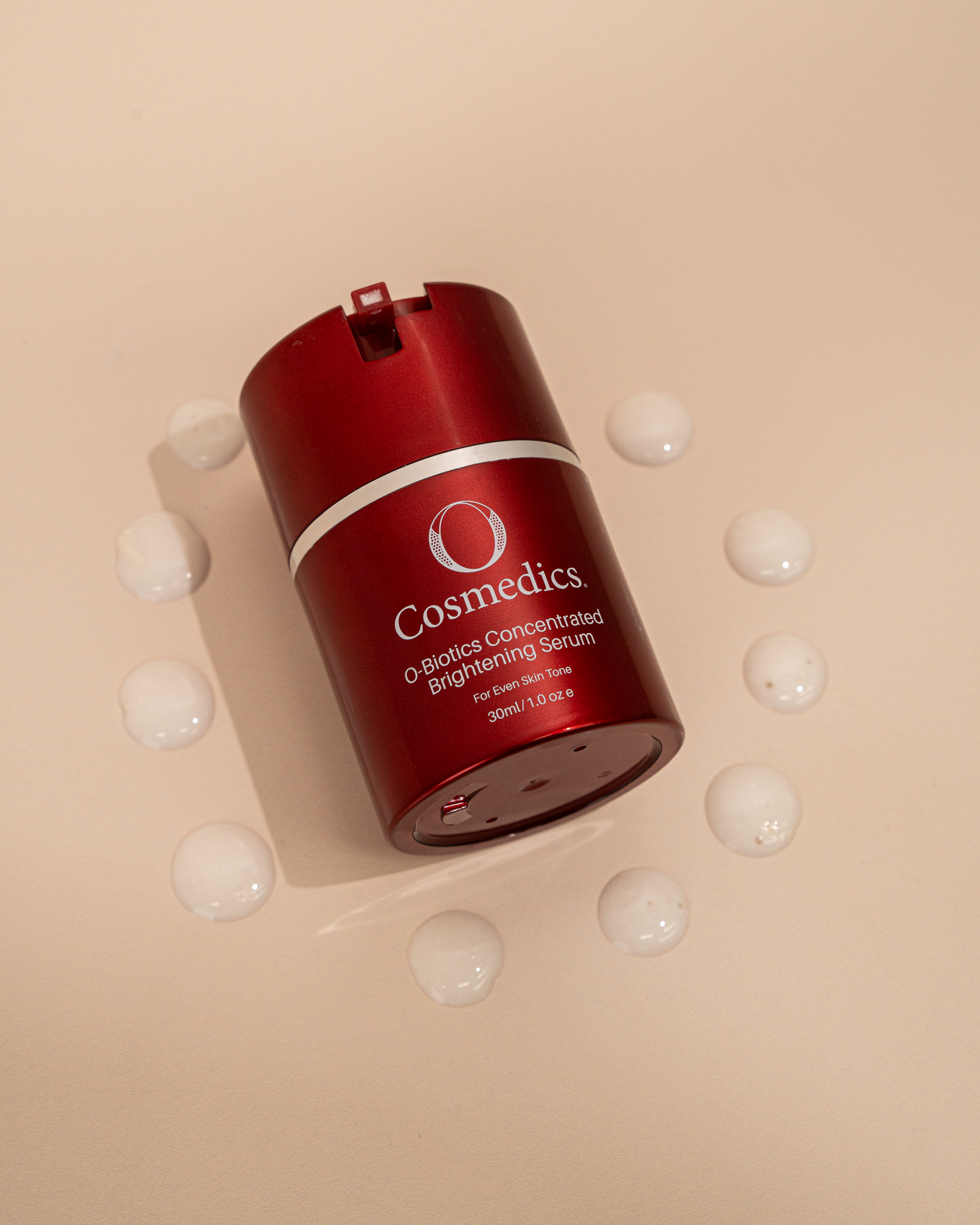 Red cosmetic serum bottle of  'O' Concentrated Brightening Serum on a beige background
