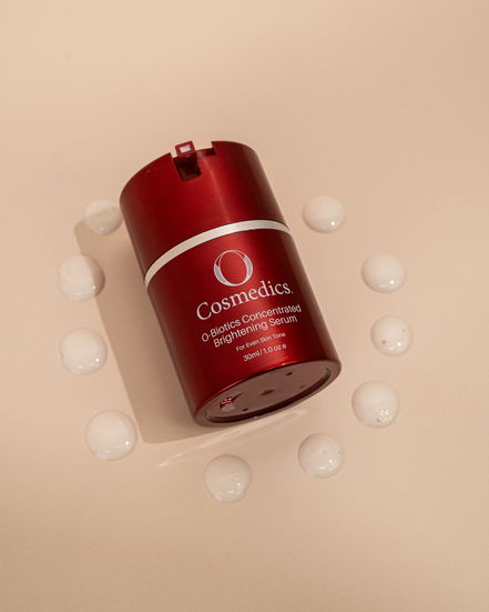 Red cosmetic serum bottle of  'O' Concentrated Brightening Serum on a beige background