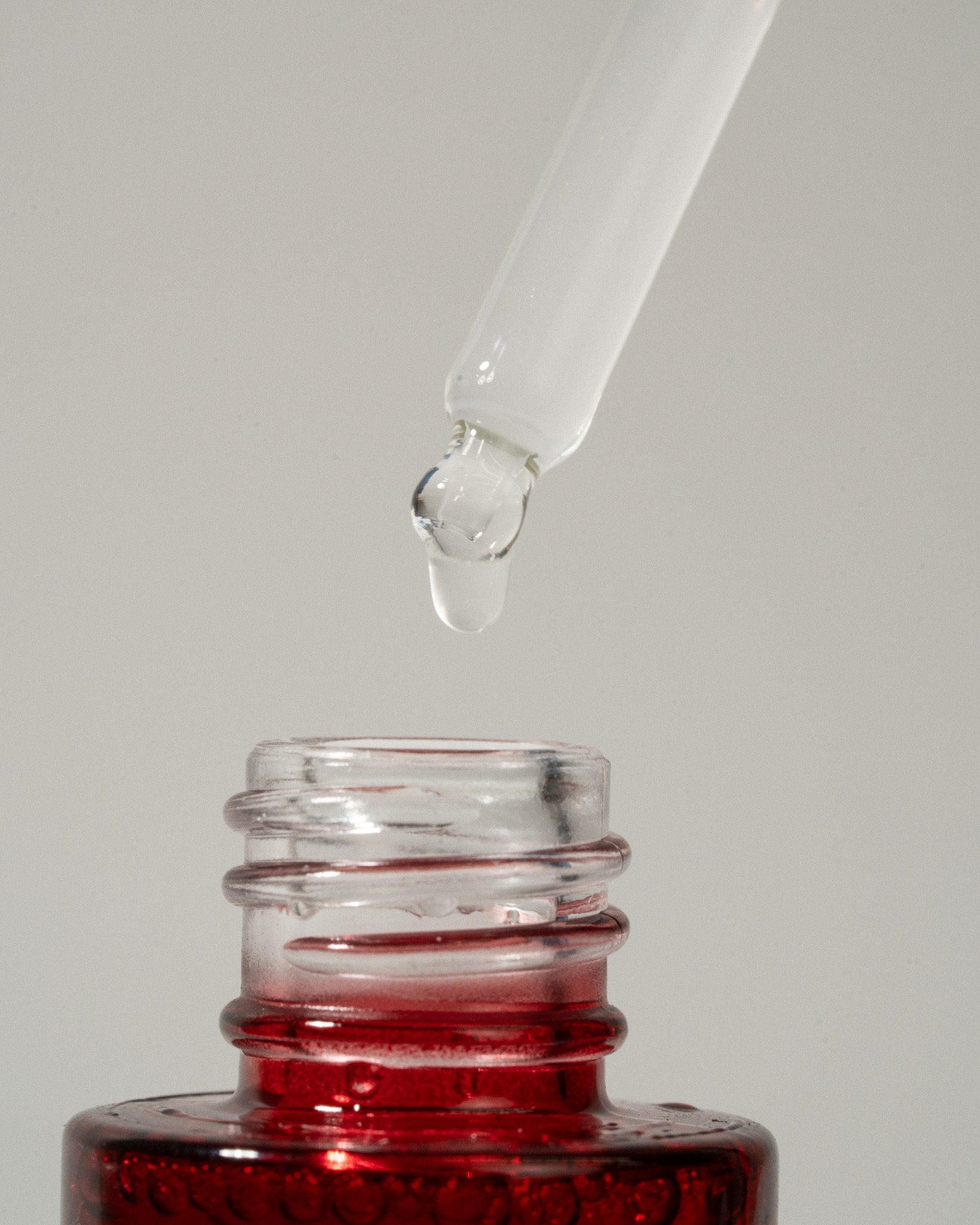 Dropper with 'O' Biotics EGF Booster in a  red bottle on a grey background