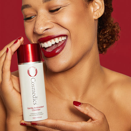 Woman holding a 'O' Gentle Antioxidant Cleanser against a red background