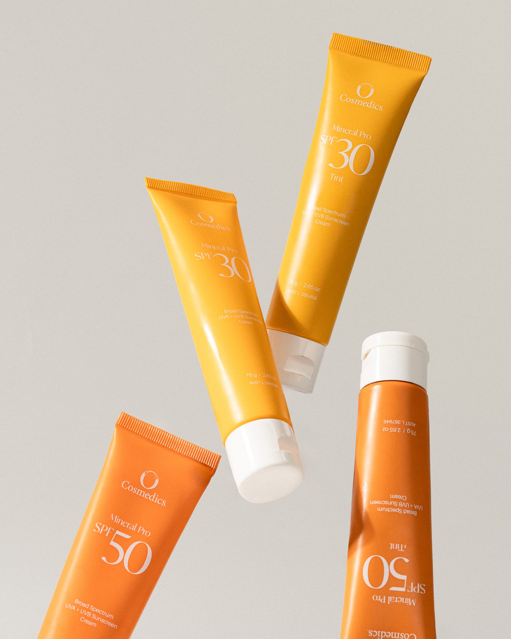 Multiple tubes of OCosmedics sunscreen with different SPF ratings on a light gray background