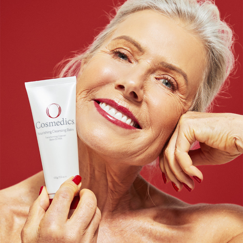 Woman holding a O Cosmedics Nourishing Cleansing Balm with a red background