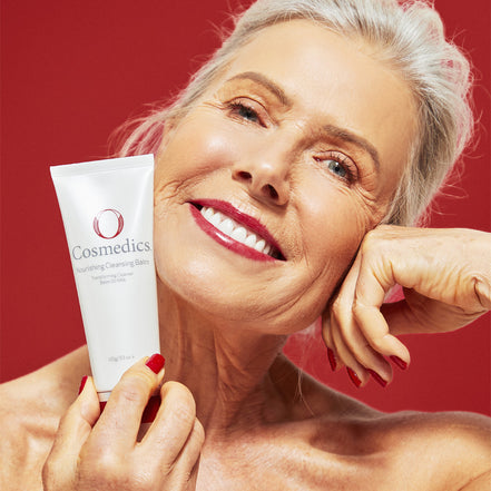 Woman holding a O Cosmedics Nourishing Cleansing Balm with a red background