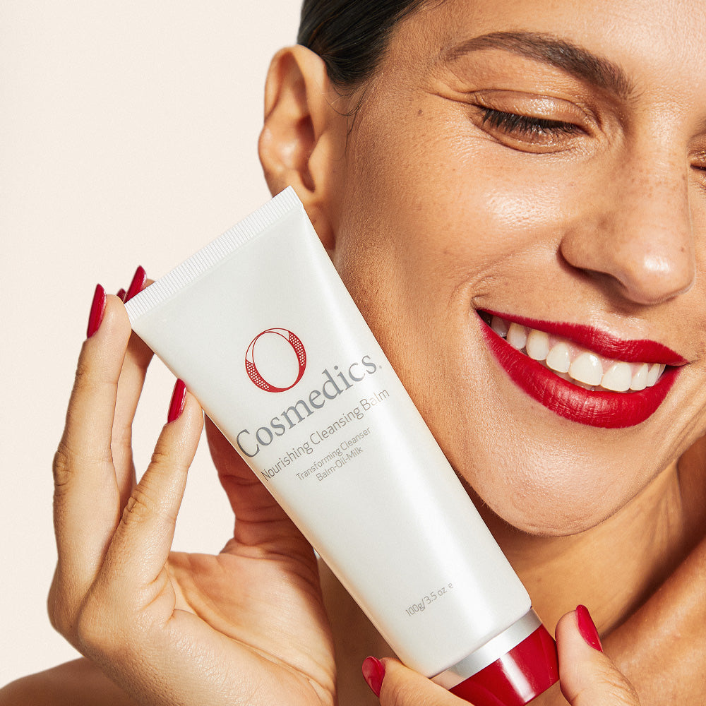 Woman holding a O Cosmedics Nourishing Cleansing Balm with a plain background