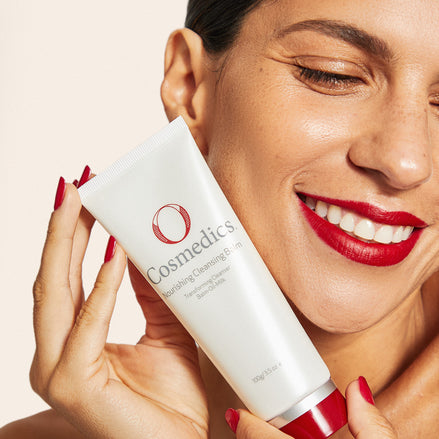 Woman holding a O Cosmedics Nourishing Cleansing Balm with a plain background