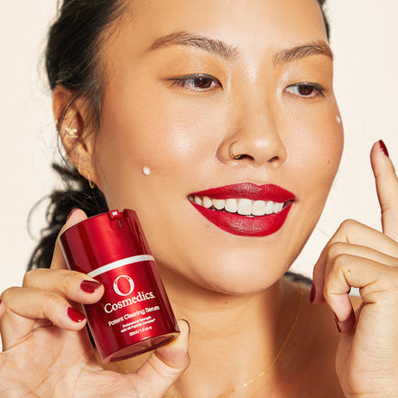 Woman holding 'O' Potent Clearing Serum with a beige background
