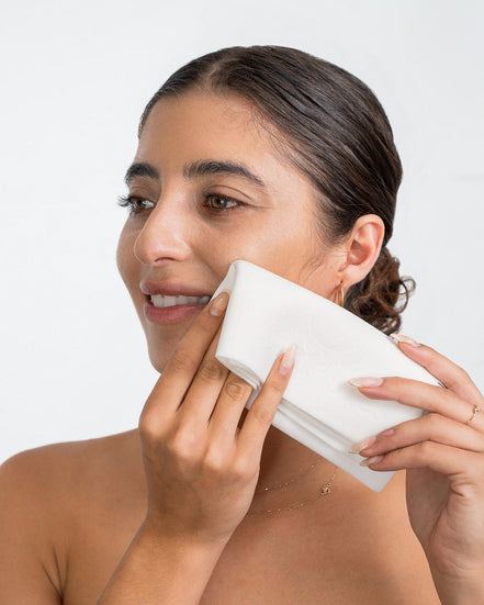 Woman cleansing her face with 'O' The Skin Shammy on neutral background