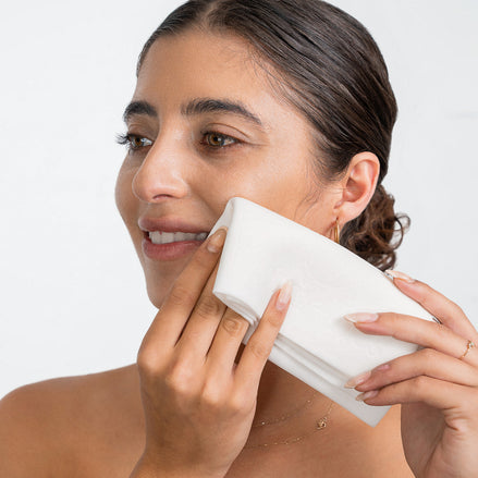 Woman cleansing her face with 'O' The Skin Shammy on neutral background