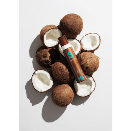 Instant Self Tan Mousse Week in Fiji surrounded by coconut halves on a white background