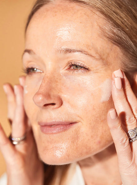 Woman applying Anti Ageing Day Cream With Tripeptides to her face with a neutral background