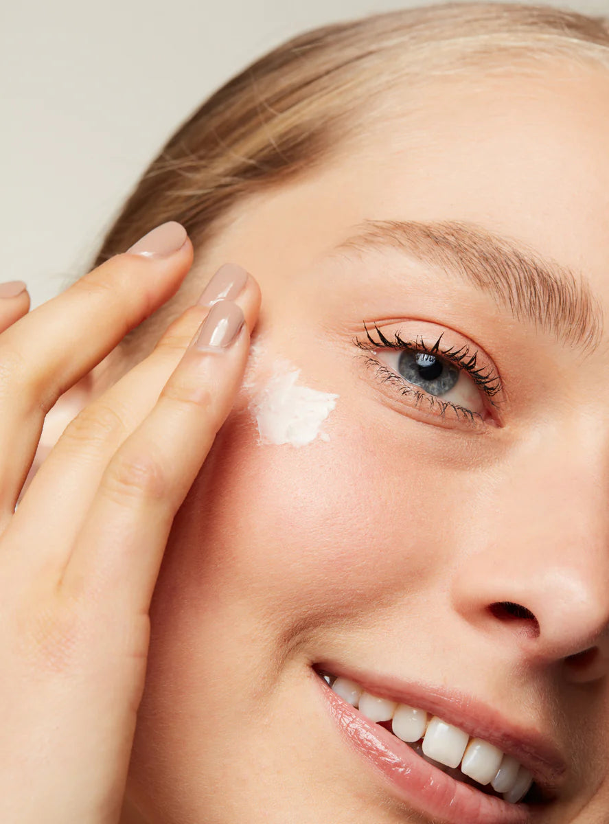 Close-up of a woman applying Anti Ageing Eye Cream With Tripeptides to their face with a neutral background